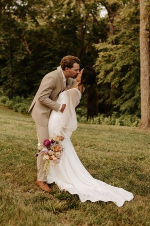 Romantic wedding photos in a grassy outdoor setting with flowing white dress and tan suit.