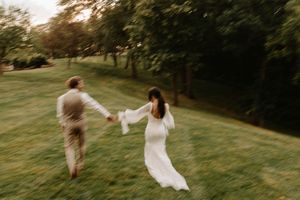A couple dances and twirls on a grassy hillside during a romantic sunset photo session.