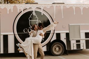 A couple dances joyfully in front of a coffee truck at an outdoor event with warm sepia tones.