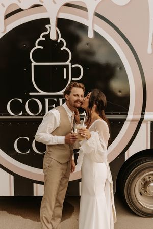 A couple shares an intimate moment in front of a coffee truck with a whipped cream logo design.