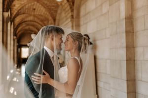 A romantic wedding scene in an ornate stone archway with natural light filtering through.