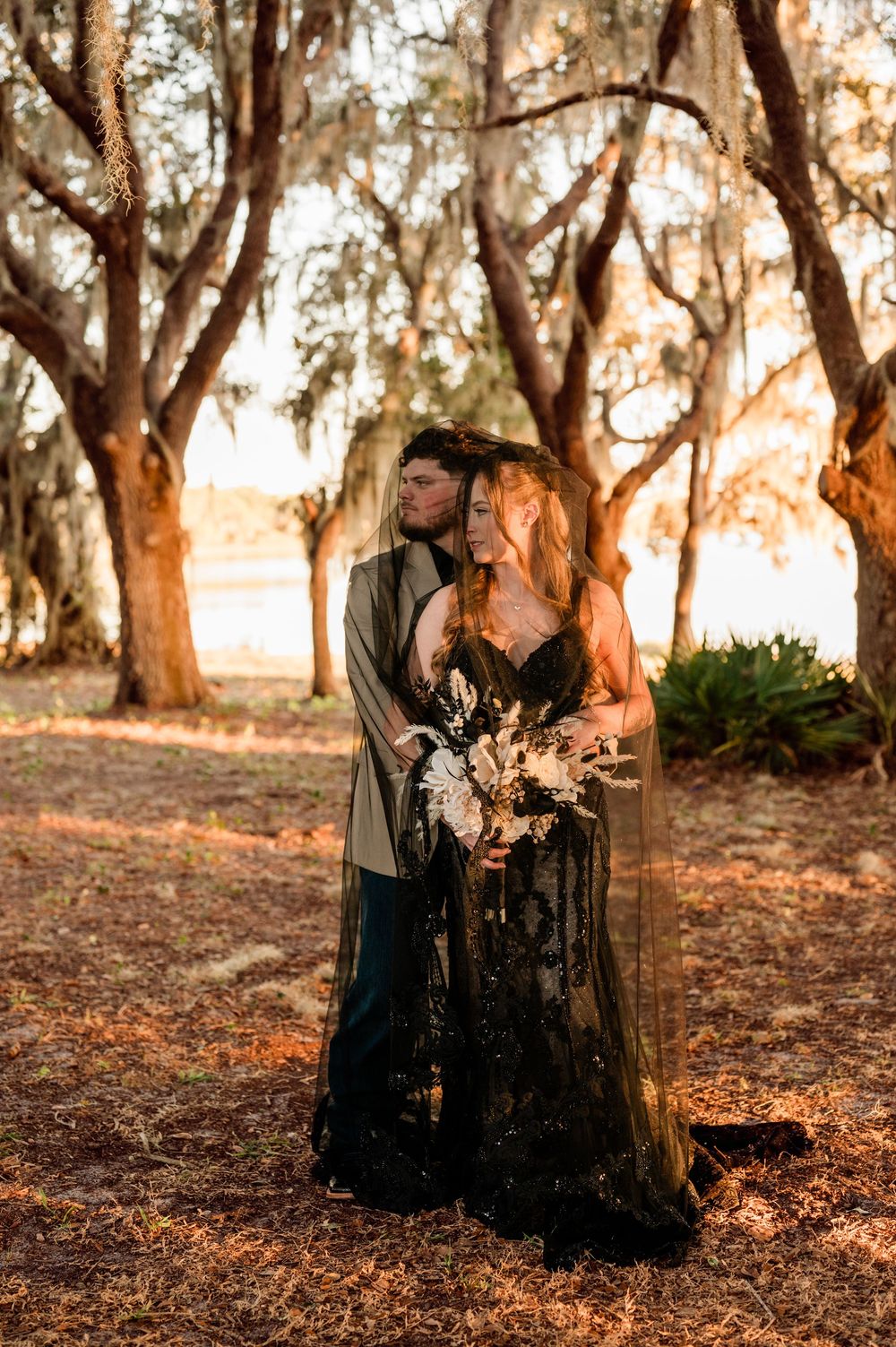 A romantic outdoor photoshoot in a wooded area with golden sunlight filtering through trees.
