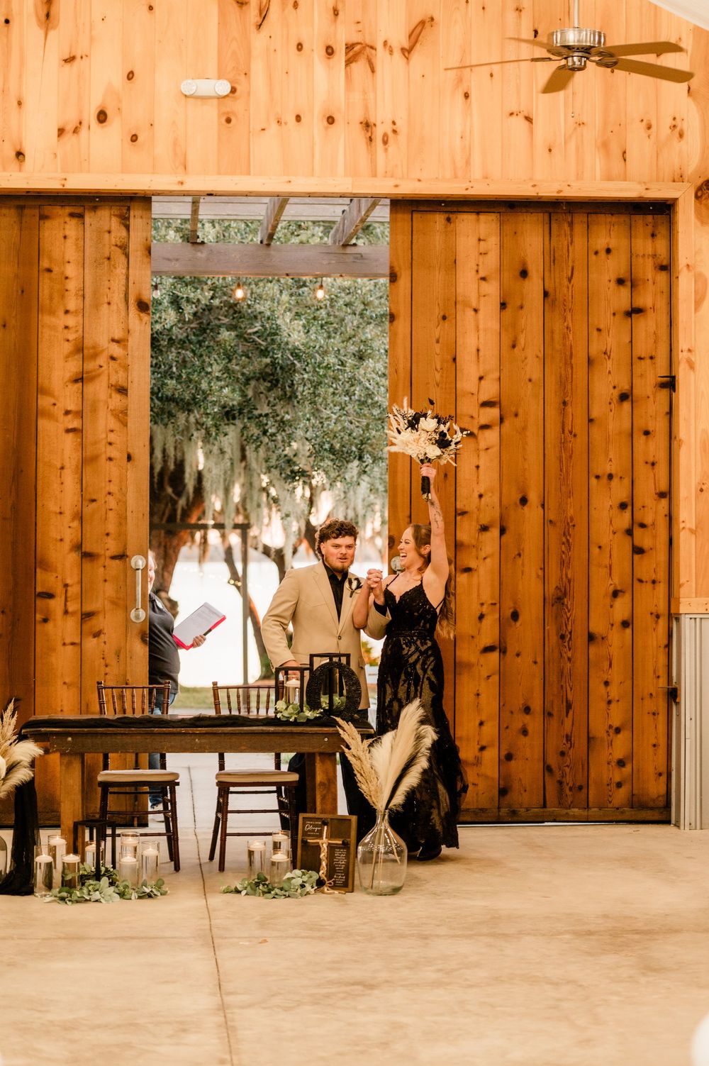 Couple dancing playfully across a rustic wooden barn interior with natural light streaming through windows.