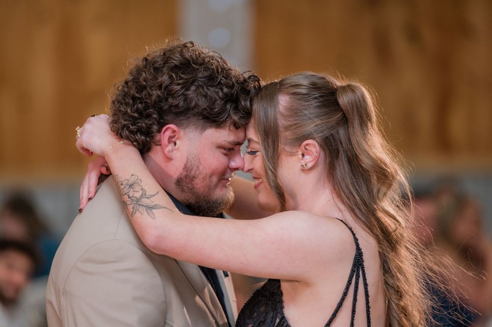 Couple dancing together in an intimate moment on a rustic wooden floor.