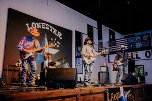 Country band performs on stage with American flag backdrop at Lonestar venue.