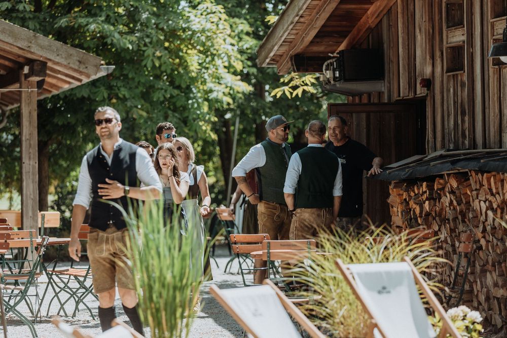 Wedding guests gather at a rustic wooden pavilion decorated for an outdoor celebration.