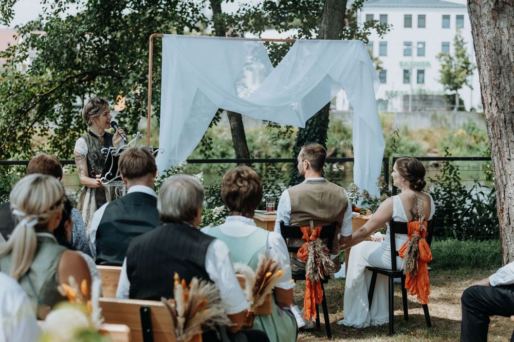 Guests watching ceremony proceedings in an outdoor woodland wedding venue.