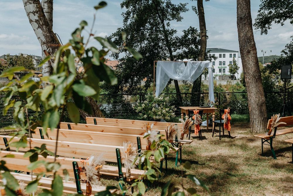 Scenic outdoor wedding venue setup with wooden benches and natural landscaping.