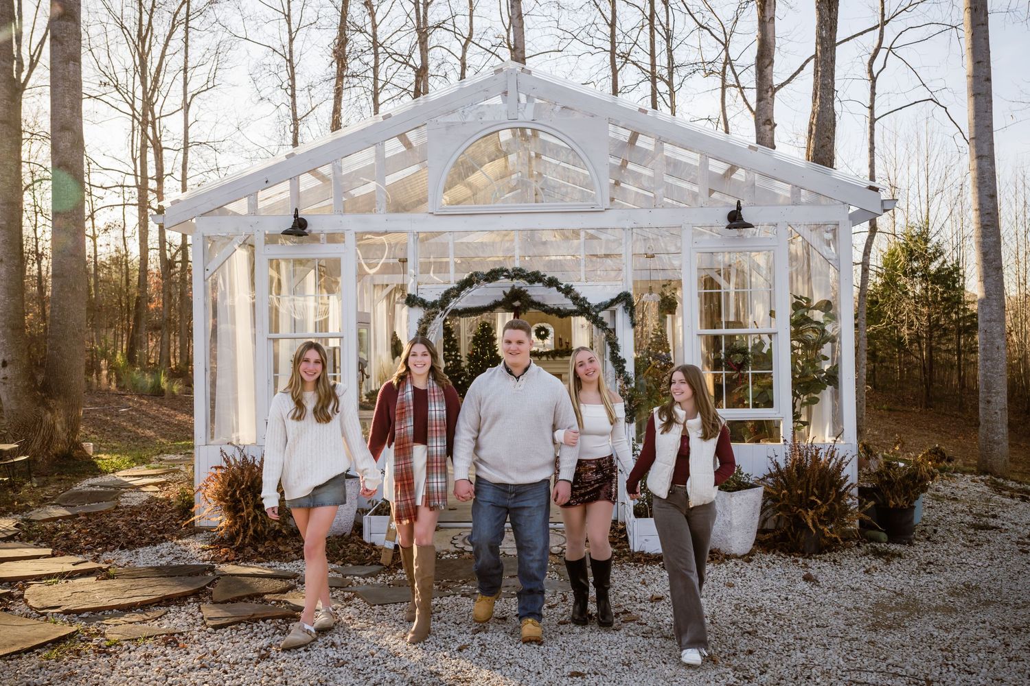 A series of outdoor family photos taken in a wooded setting with a white greenhouse structure in the background.