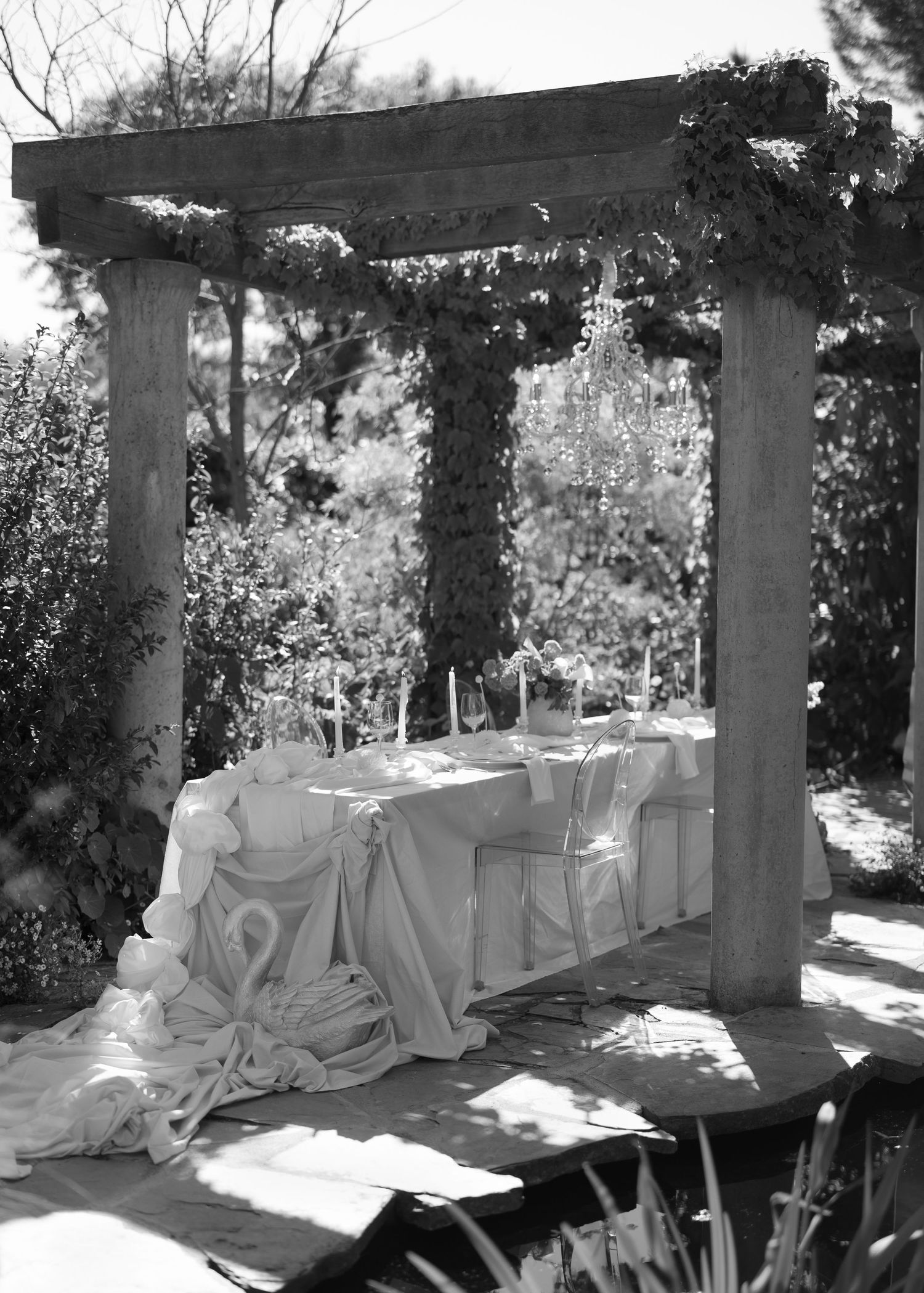 A covered outdoor patio with white draped furniture and stone columns casting shadows in bright sunlight at Al Ru Farm in Adelaide