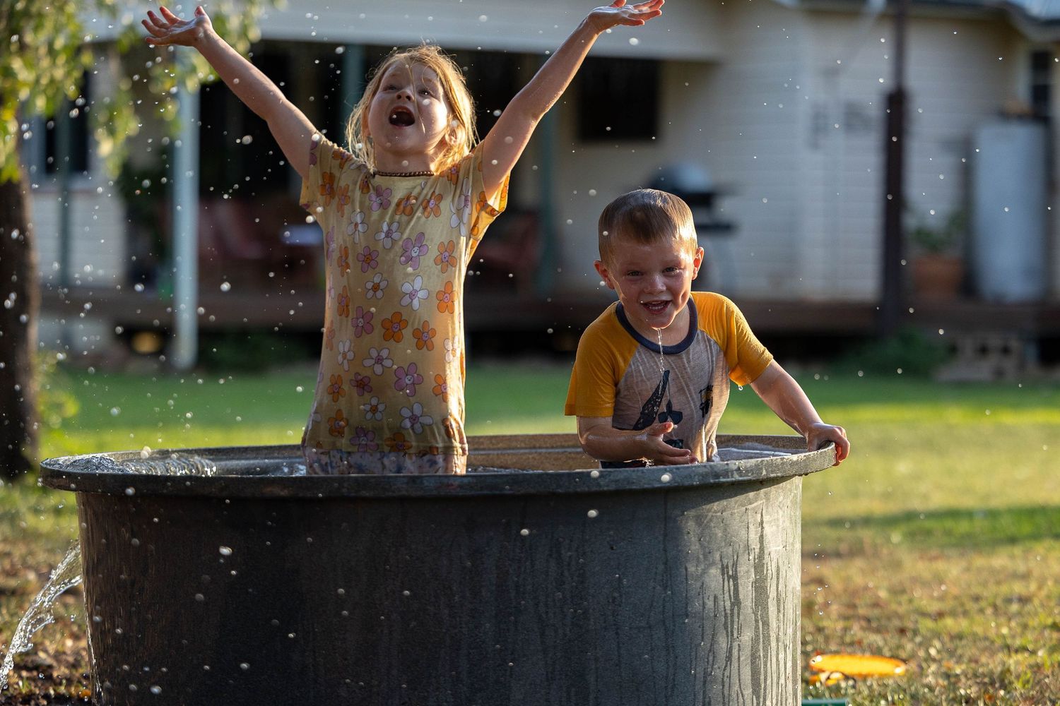 Little girl throwing arms in the air while swimming in a cattle trough