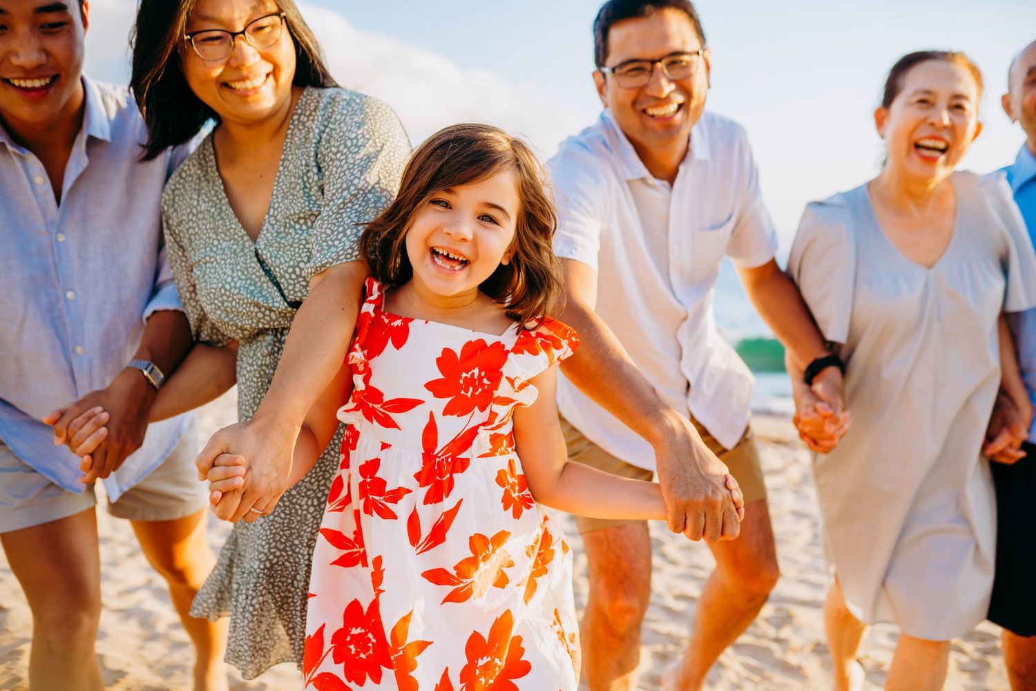 Joyful family members running and laughing together on a sunny beach. best hawaii family photographer kihei wailea kaanapali makena