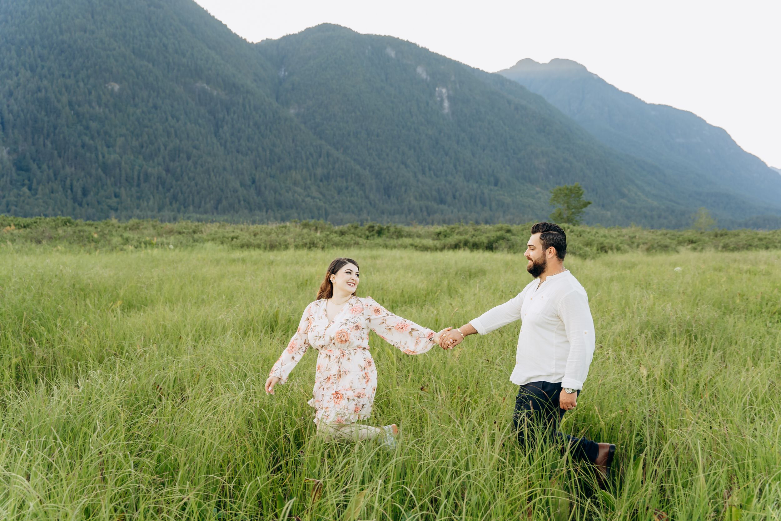 Couple walking and dancing together through scenic mountain meadows in a romantic photoshoot sequence.