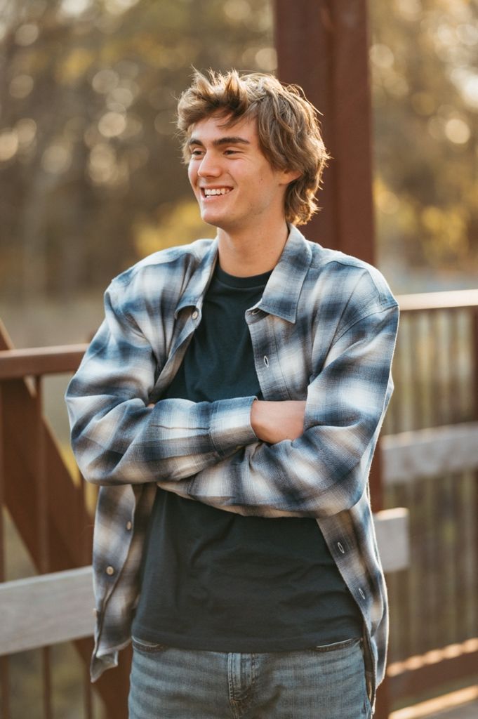 Candid lifestyle photo featuring a person in blue jeans and plaid shirt against wooden pillars.