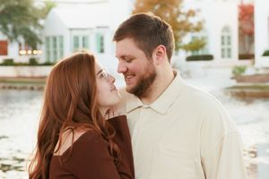 A romantic couple shares tender moments during an outdoor engagement photo session in a sunlit garden setting.