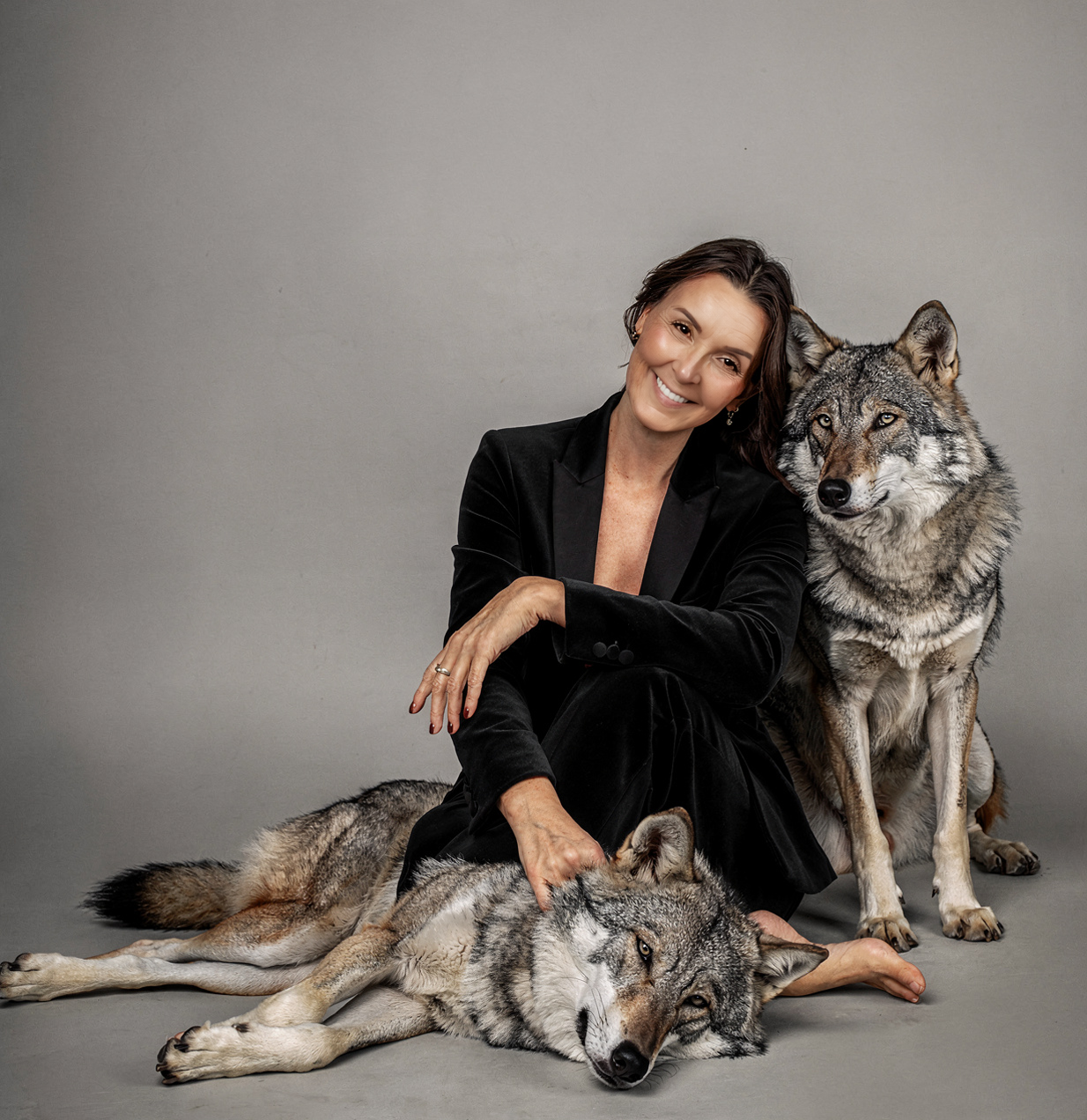 Professional studio portraits featuring a large wolf-like dog and person in black attire posing together against a gray backdrop.