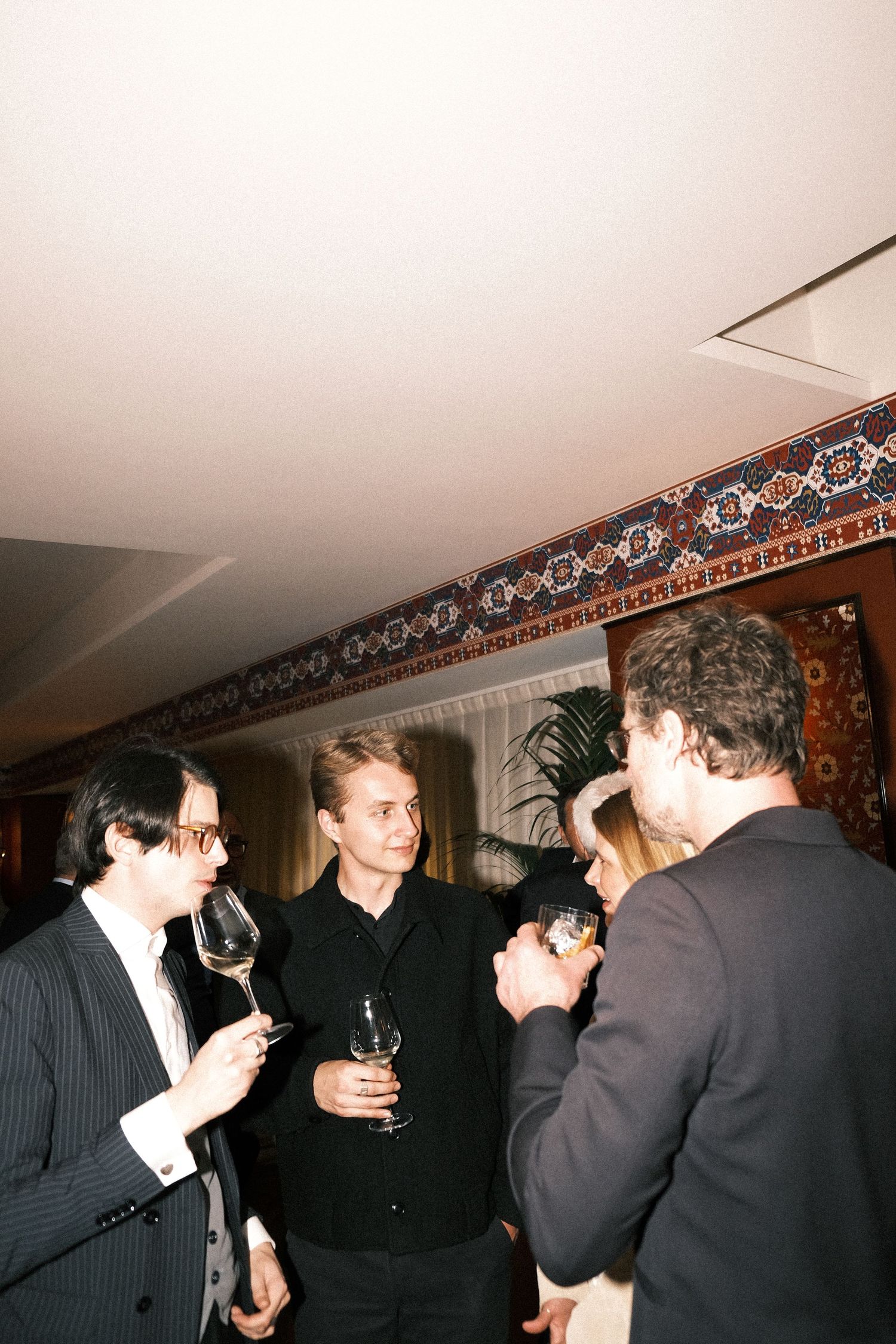 A sequence of candid party photos showing people in formal attire socializing and drinking at an indoor gathering.