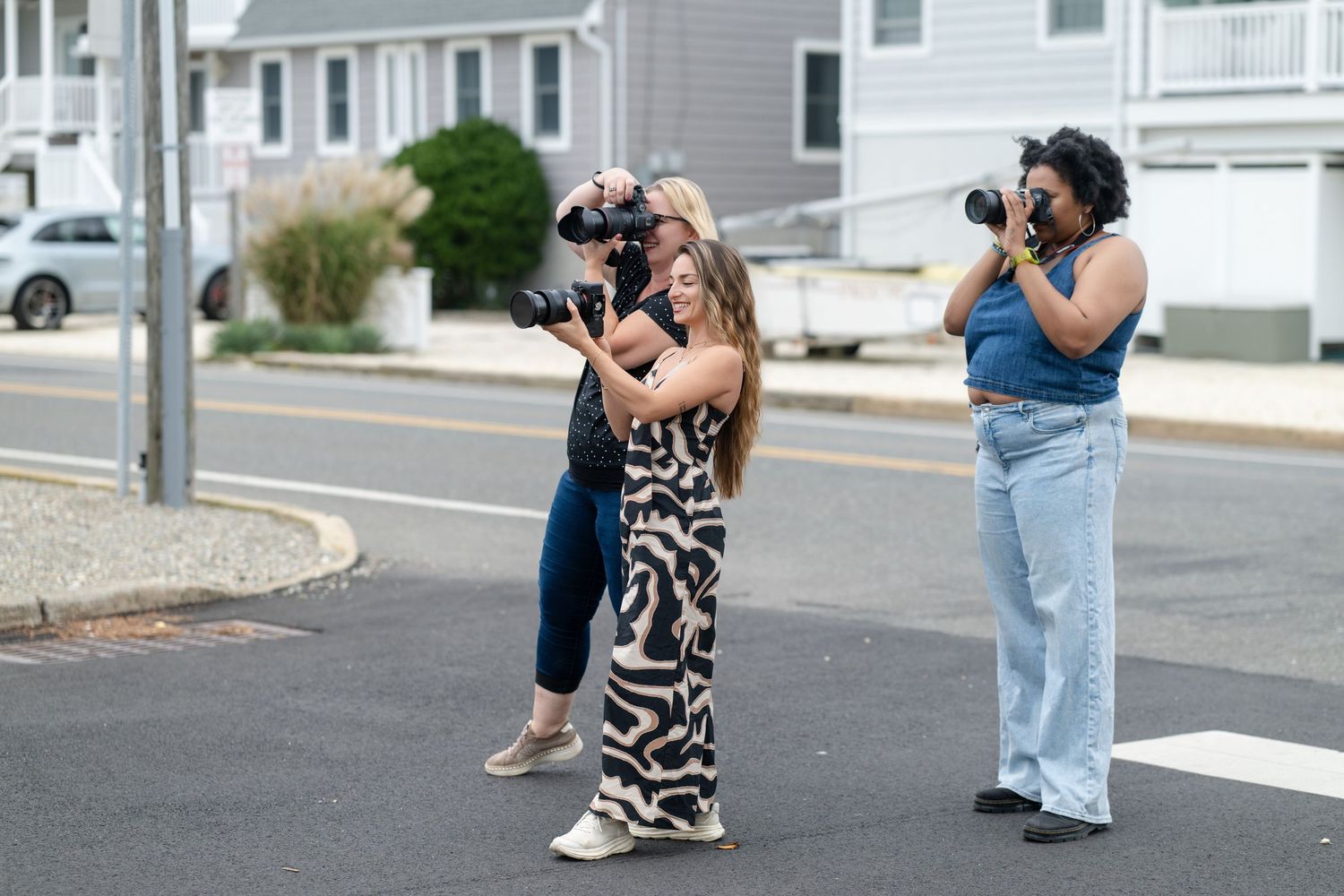 Group of photographers with cameras taking pictures outdoors on a residential street.