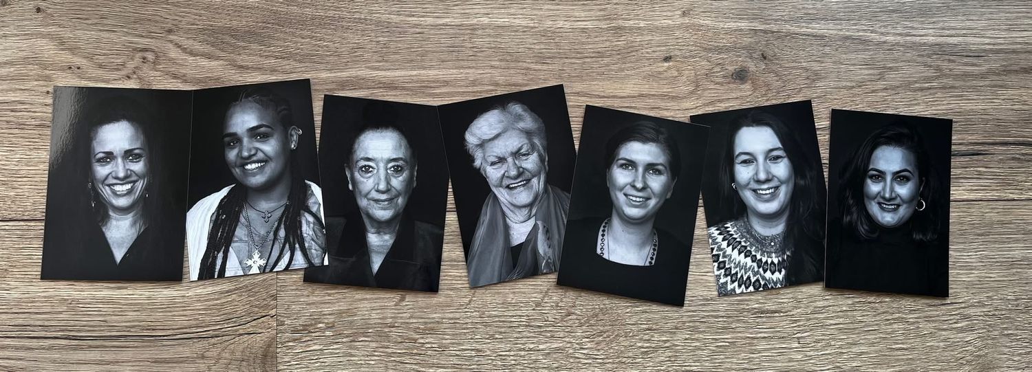 A row of black and white portrait photographs displayed on a wooden surface.