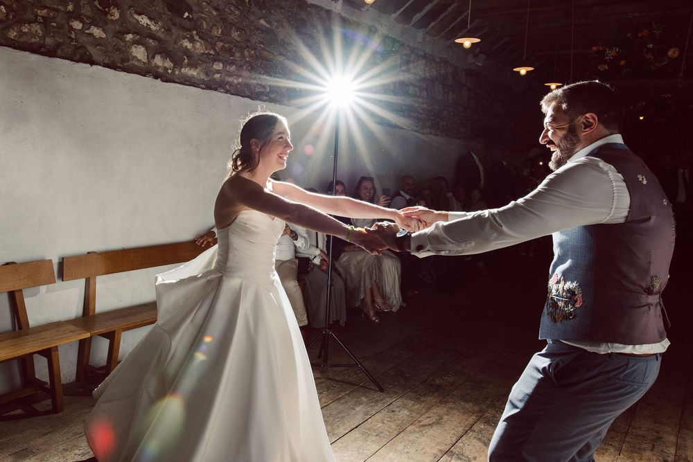 A couple dances together at a wedding reception with a dramatic starburst light effect in the background.