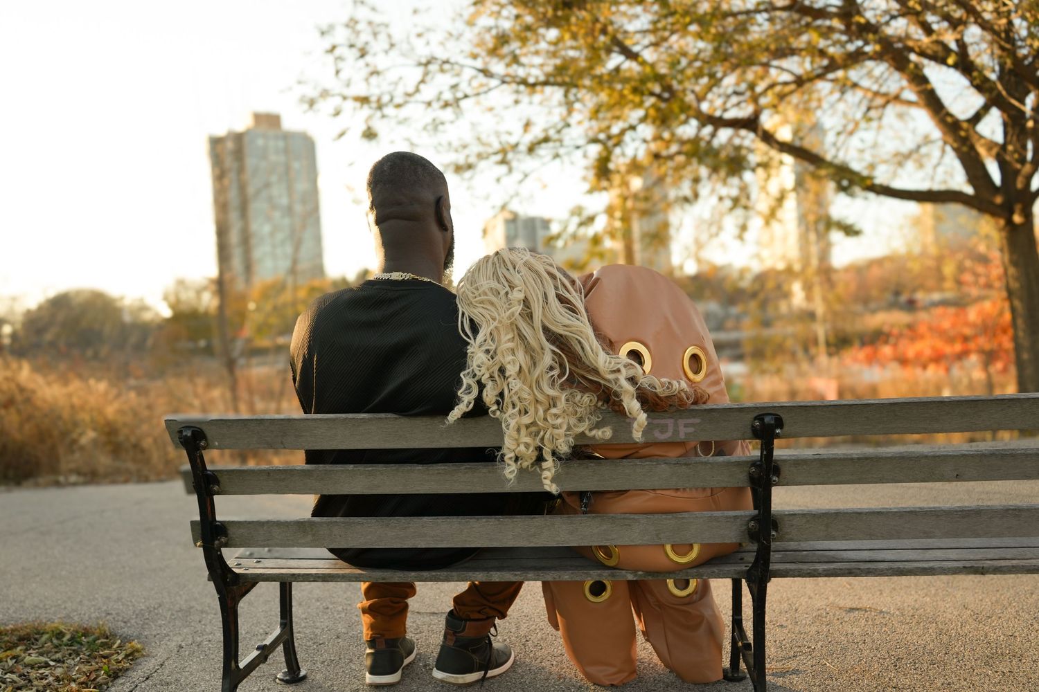 People sit on a park bench at sunset overlooking the city skyline on a peaceful autumn evening | Sydney Allen Photography
