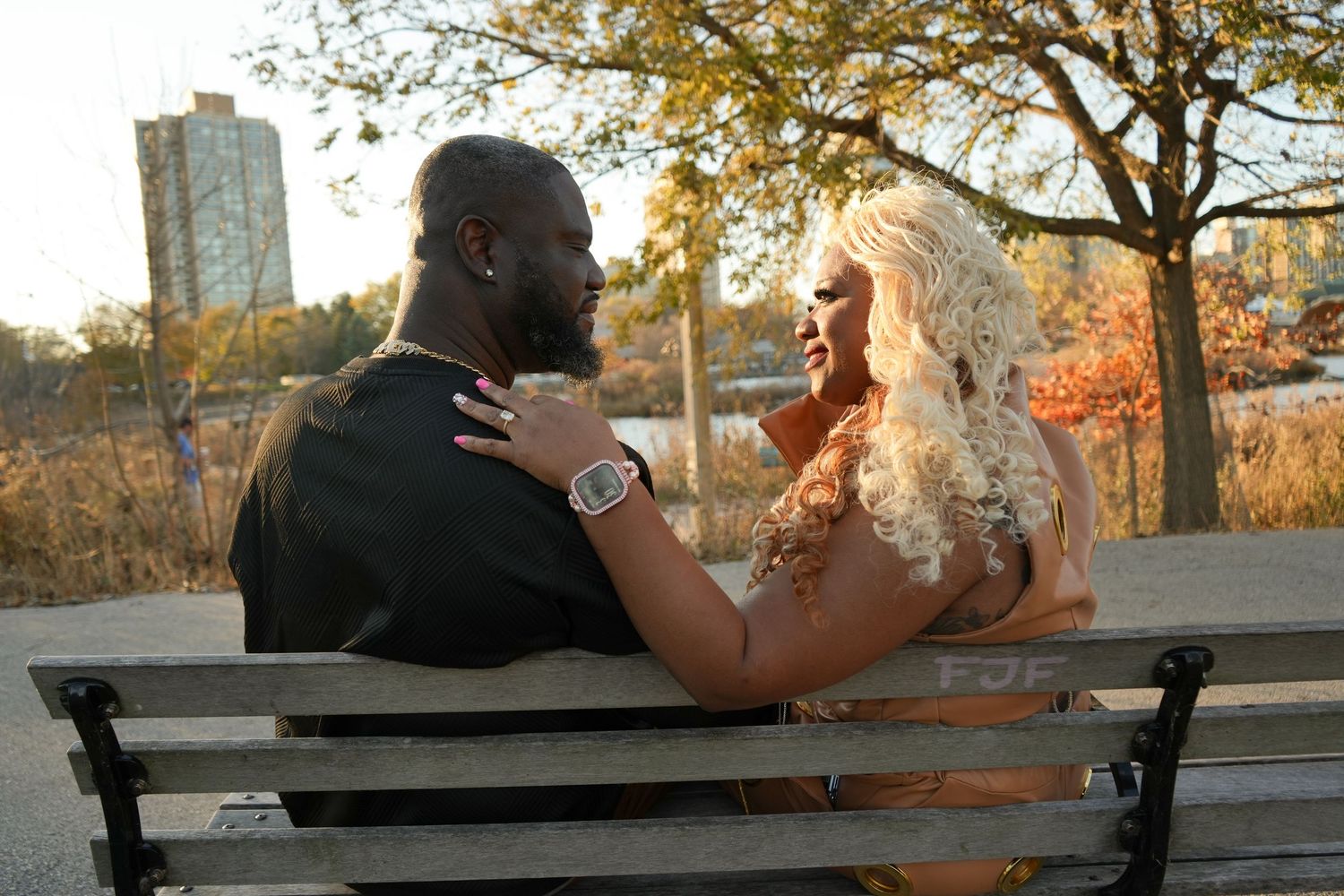 A couple sits together on a wooden bench at sunset in a park during autumn | Sydney Allen Photography