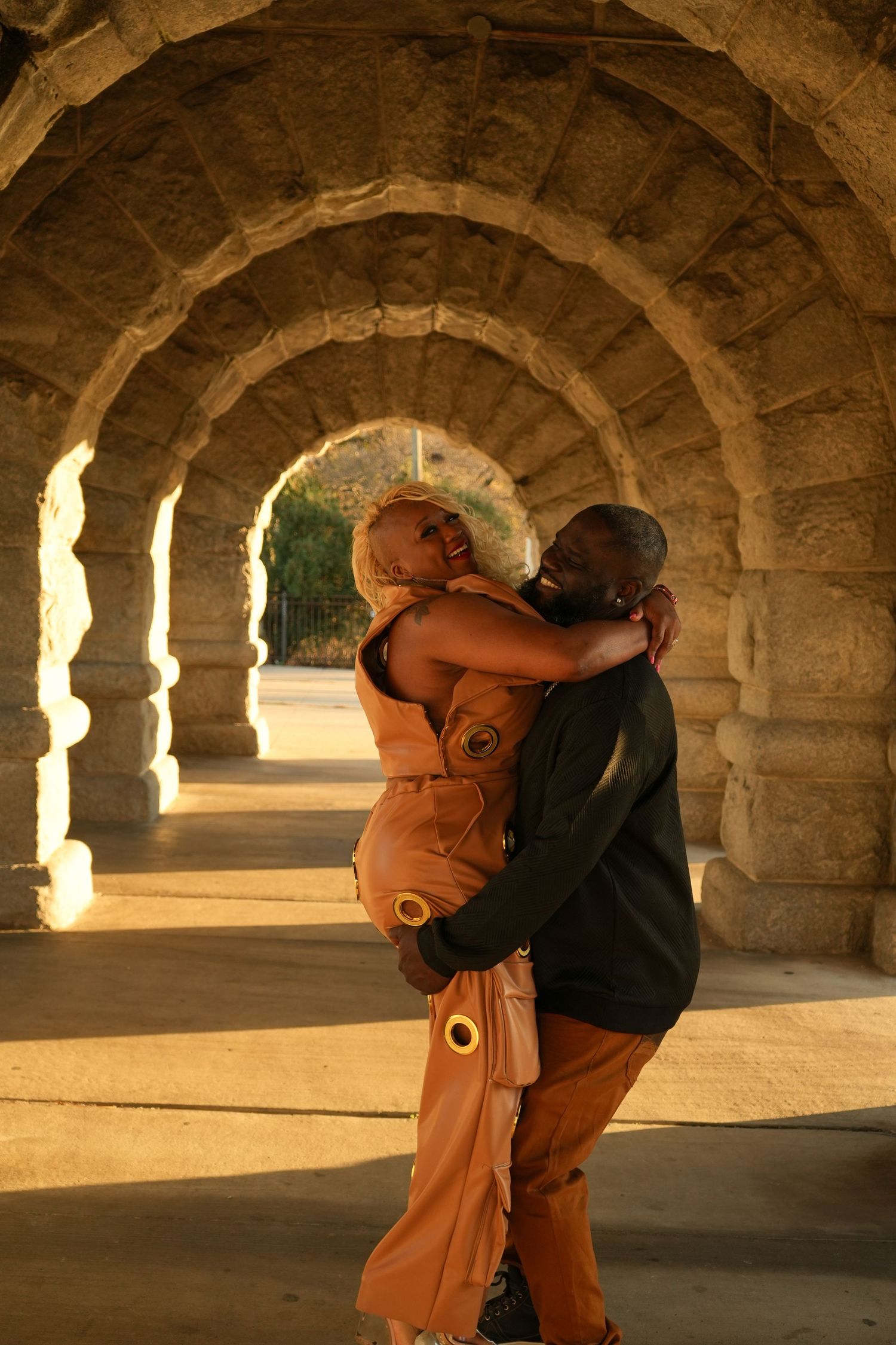A couple embraces in a stone archway corridor during golden hour lighting | Sydney Allen Photography