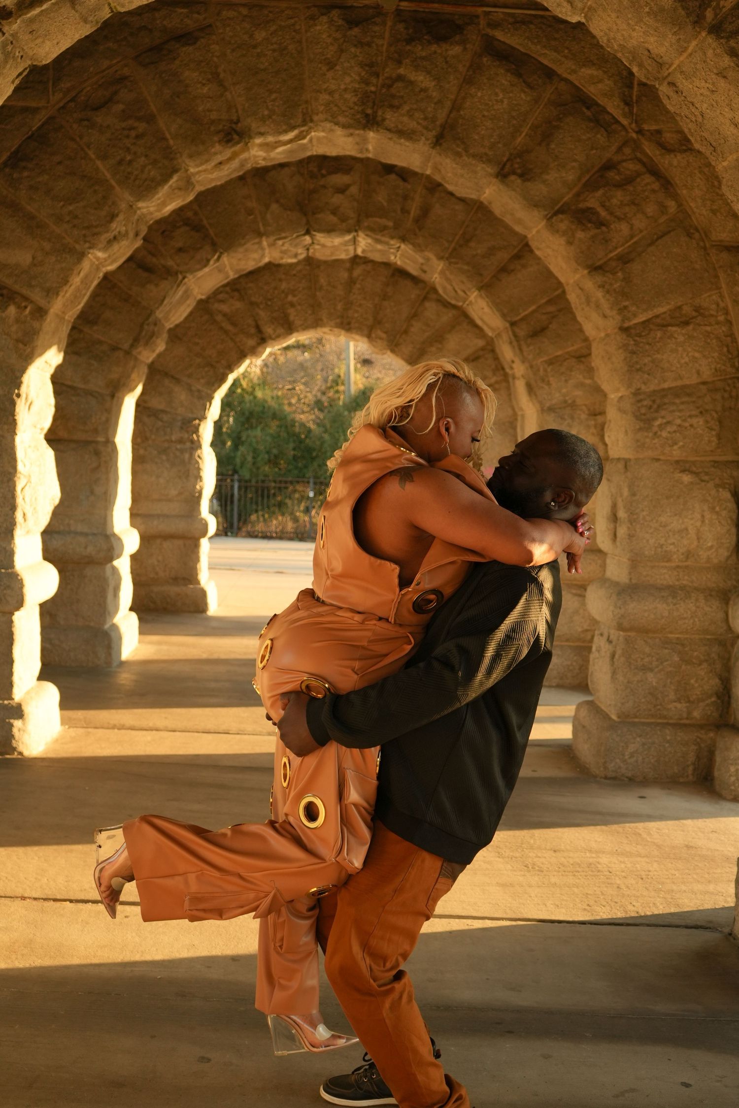 Two dancers perform a dramatic lift sequence under stone arches with warm sunlight streaming through the columns | Sydney Allen Photography