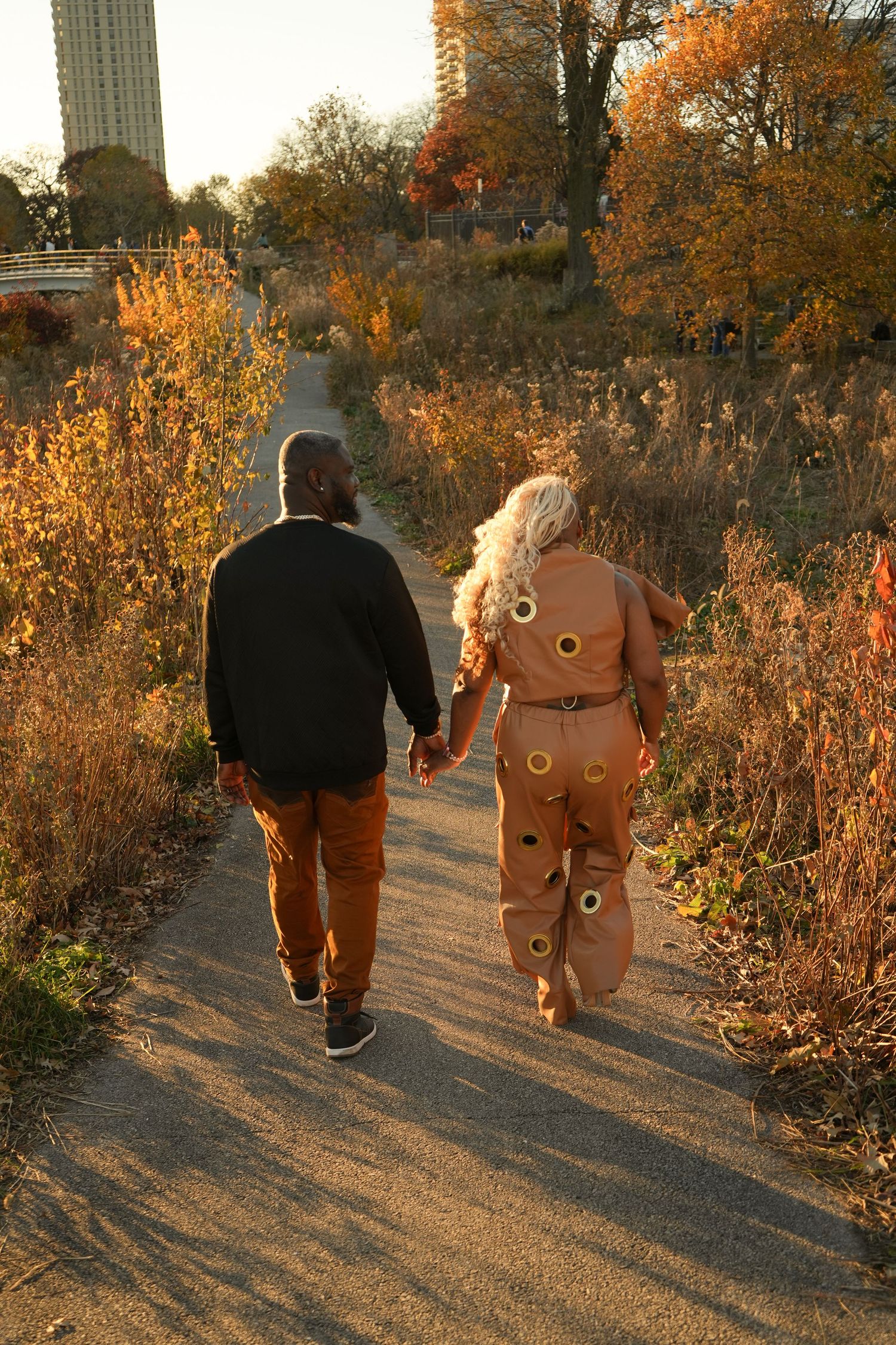 A couple walks hand in hand on an autumn path with golden foliage | Sydney Allen Photography