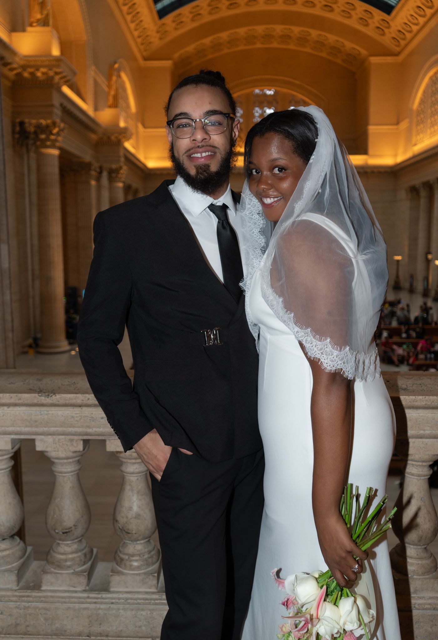 Bride and groom pose elegantly inside ornate marble hall on their wedding day.