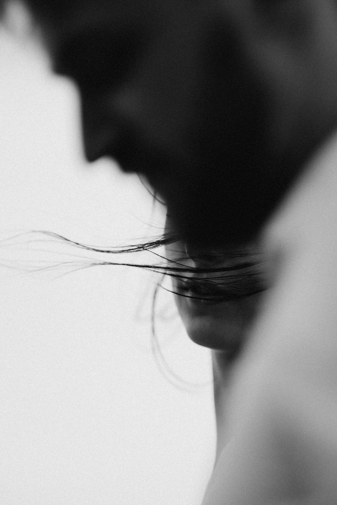 Black and white artistic portrait of couple facing each other closely.