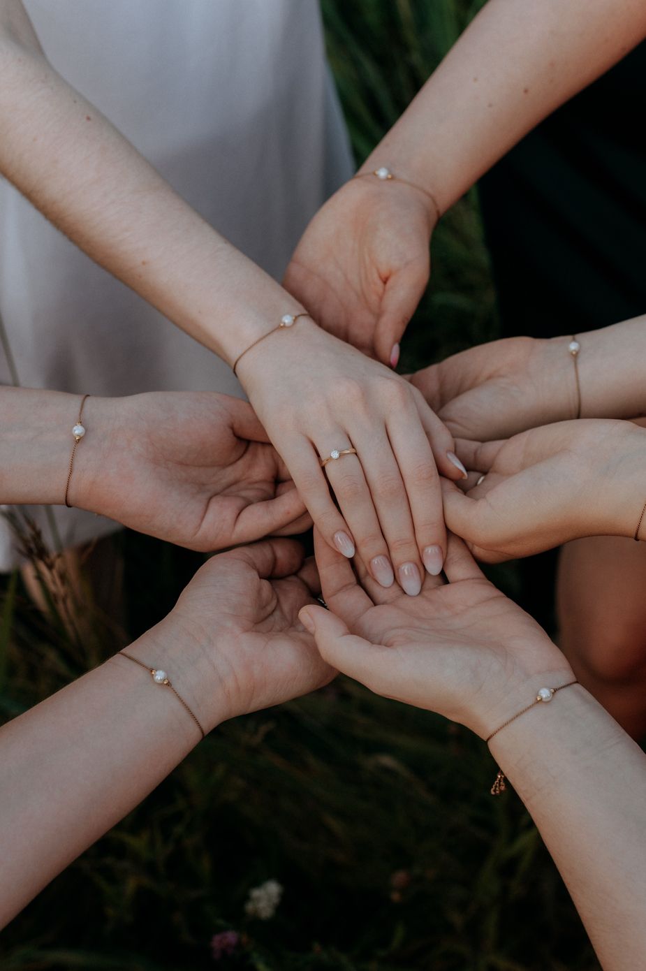 Multiple hands join together in unity showing support and teamwork against a dark background.