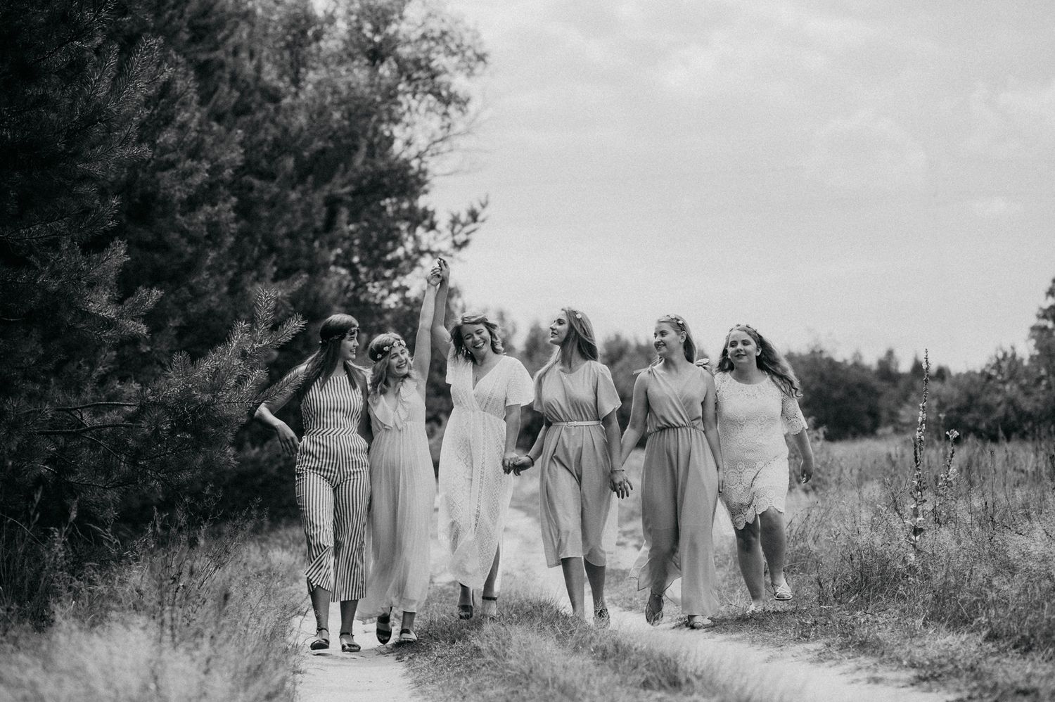 A black and white panoramic sequence showing a group walking together through a rural path in vintage clothing.
