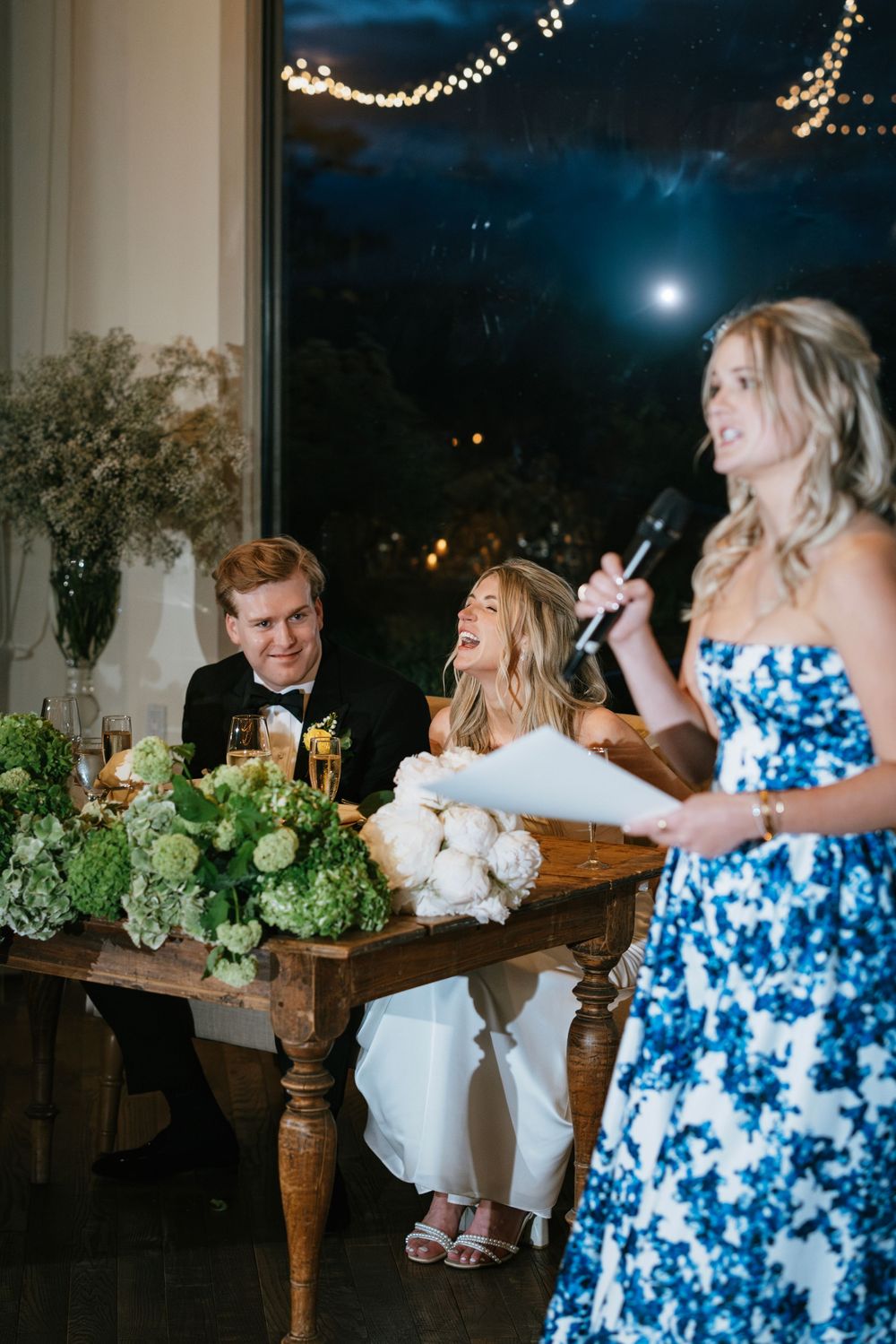 Wedding guests in blue and white tie-dye dresses dance and celebrate at an evening reception.