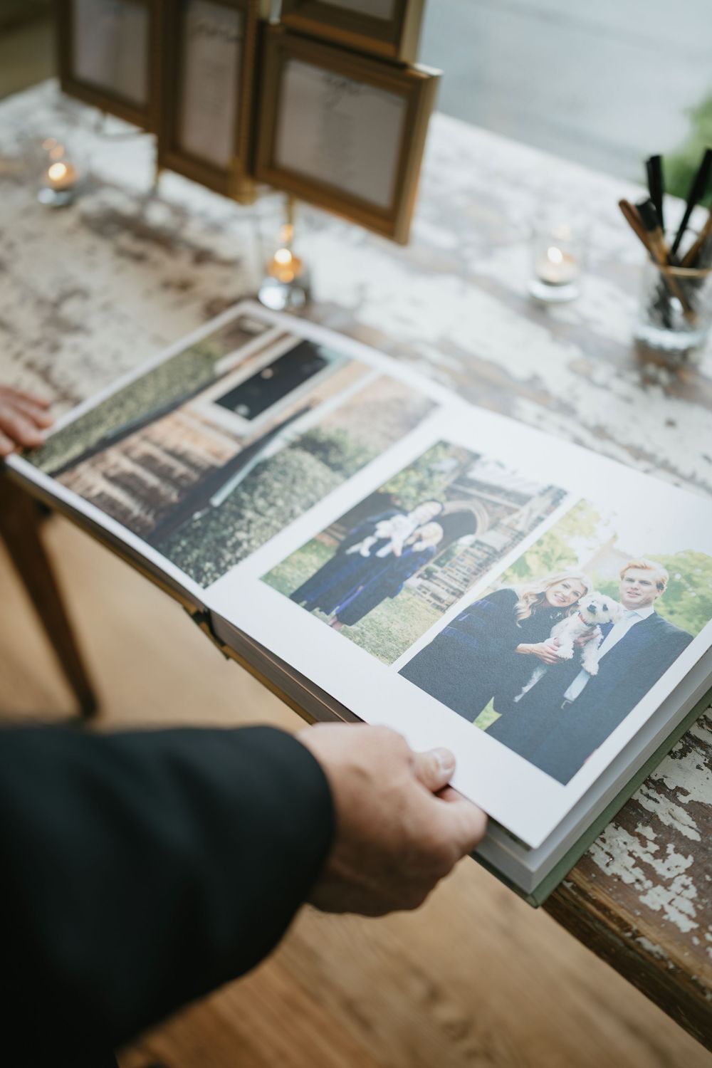 A series of wedding photo album pages being flipped through showing black and white photographs on a wooden surface.
