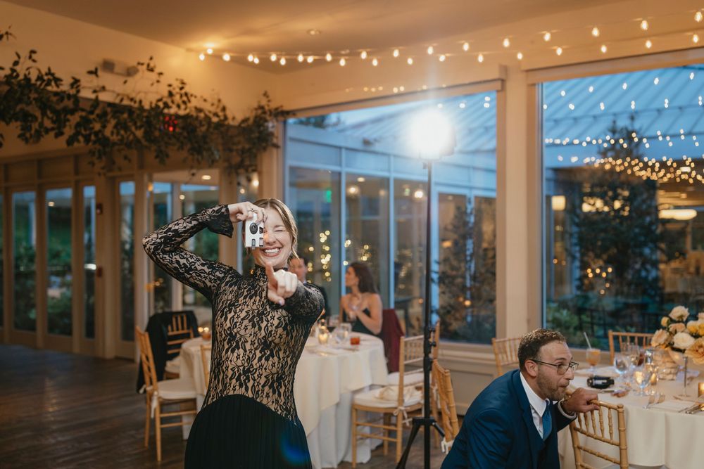 String lights illuminate a modern reception venue with large windows and elegant decor for an evening celebration.