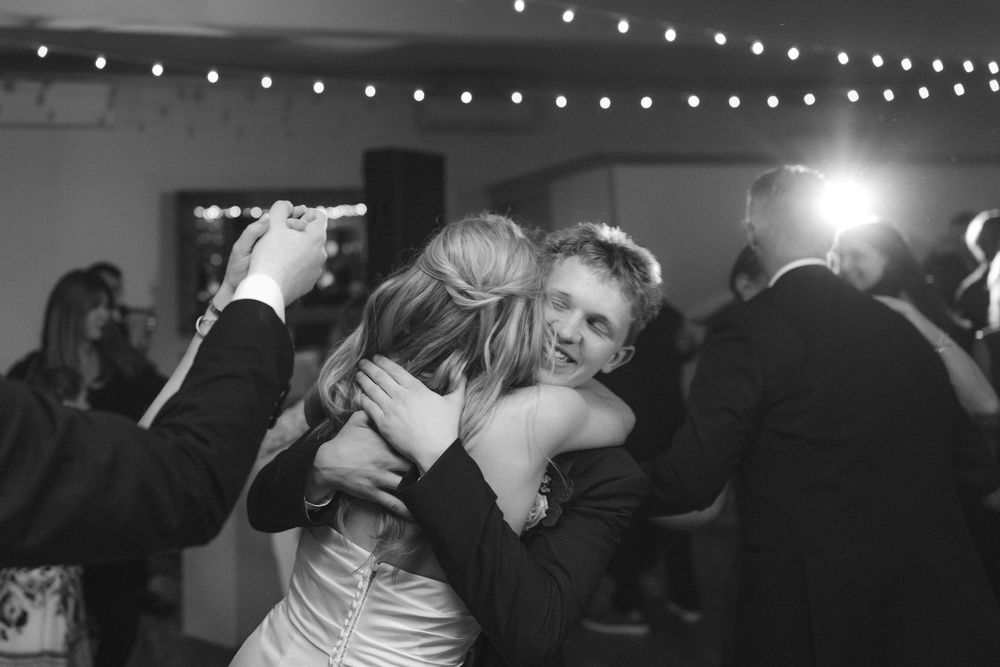 People dancing and celebrating at a lively party with string lights overhead in black and white.