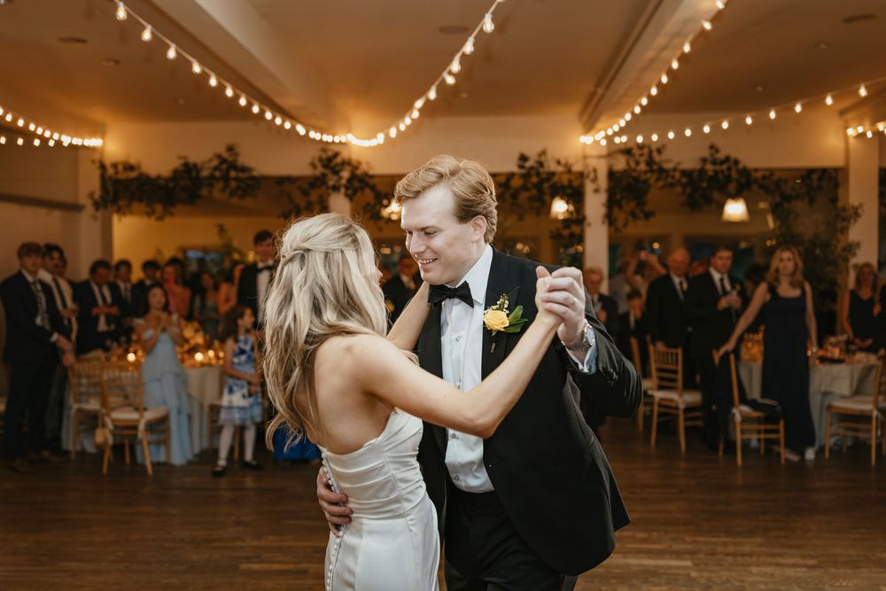 Wedding reception venue decorated with romantic string lights as guests dance and celebrate.