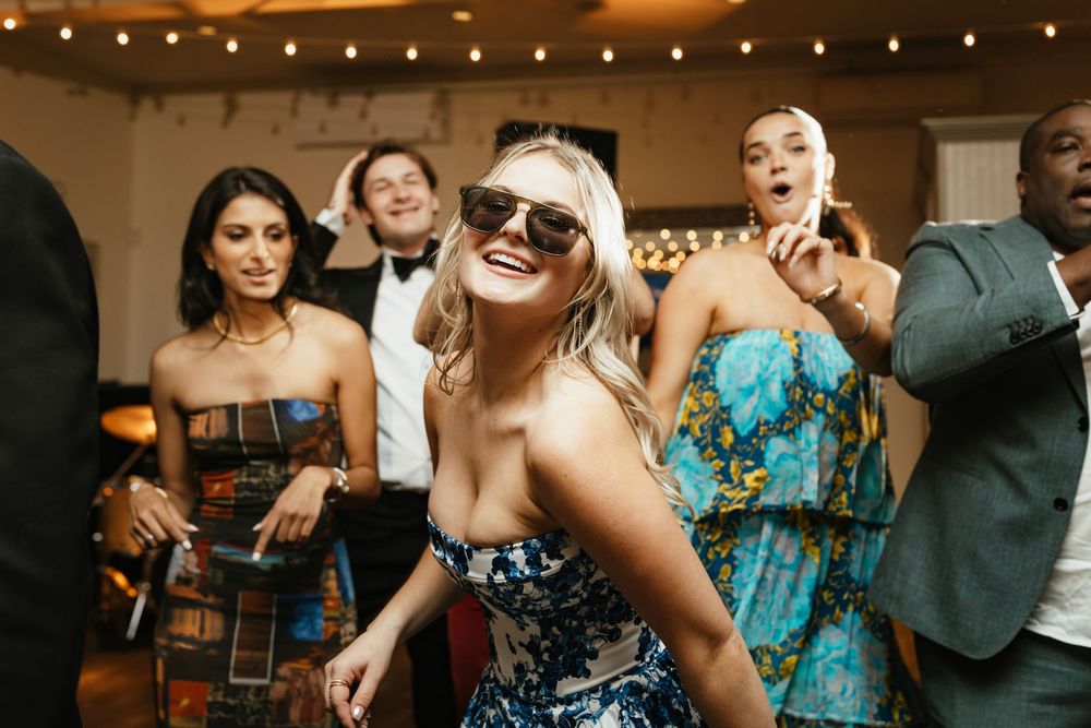 Wedding guests enjoying a lively moment during the reception under twinkling string lights.