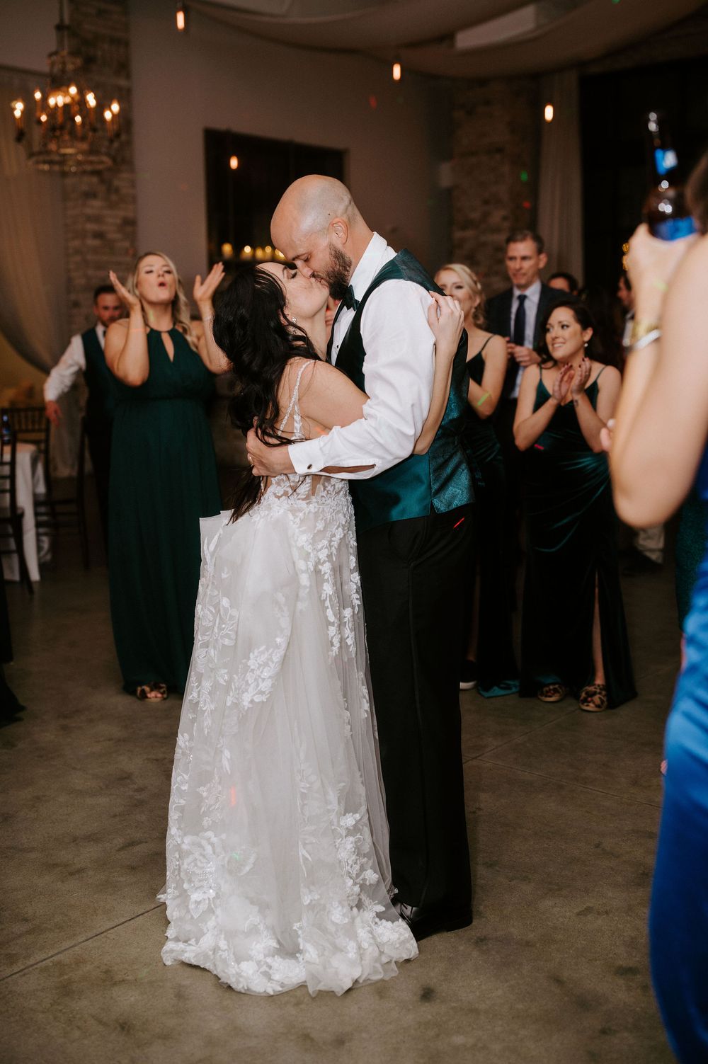 A couple shares a romantic dance at their wedding reception while guests look on in the background.