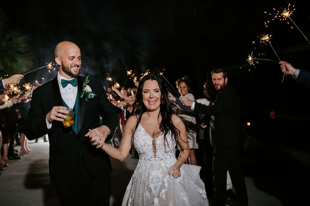 Wedding guests hold sparklers during a nighttime celebration creating a magical atmosphere at an outdoor reception.
