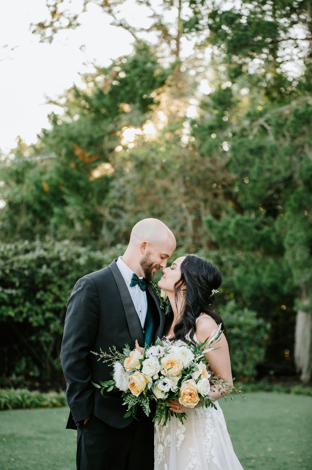 Romantic wedding couple shares tender moments in a garden setting with lush greenery and soft natural lighting.