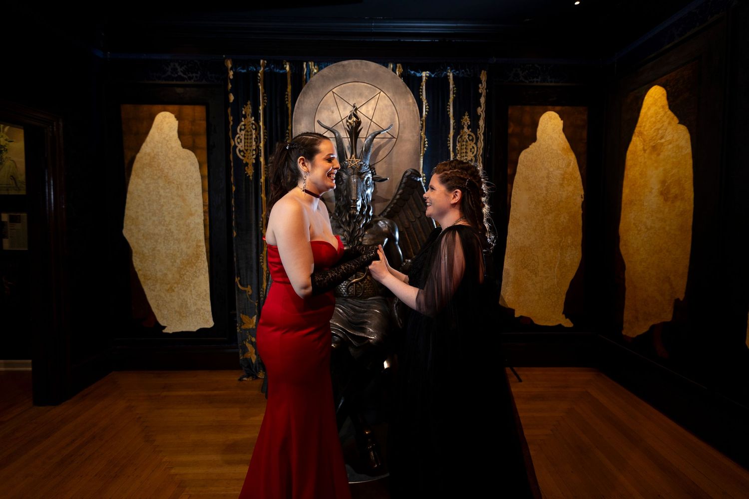 Two people in formal attire dance together in an elegant room with illuminated gold panels and dark decor.