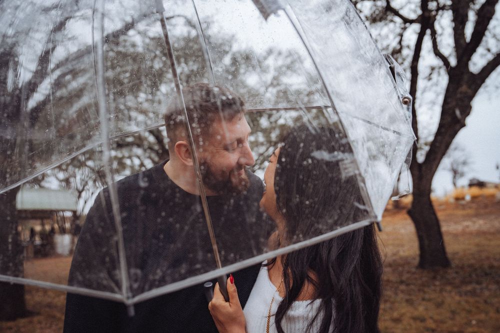 A couple embraces beneath a transparent umbrella on a foggy autumn day in nature.