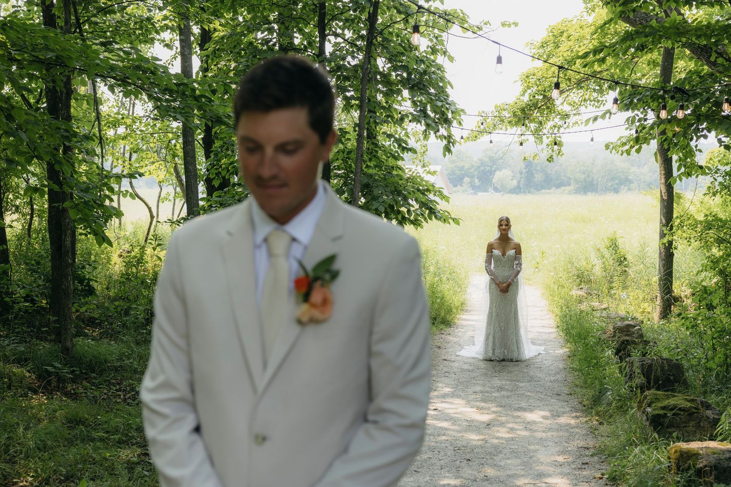 A wedding party walks along a tree-lined path in a scenic outdoor setting during a summer ceremony.