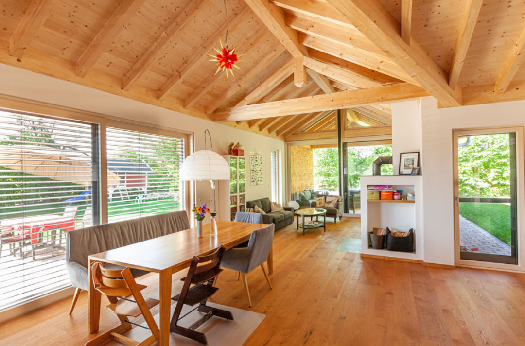Modern wooden attic room with sloped ceiling, large windows, and contemporary furniture in warm natural lighting.