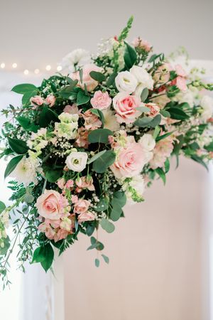 Elegant floral arrangement with pink roses, white blooms and eucalyptus greenery against a light neutral background.