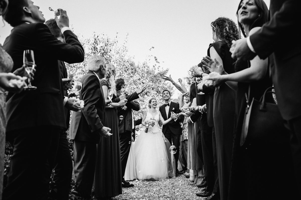 bride and groom getting showered with rose petals in tunnel of love