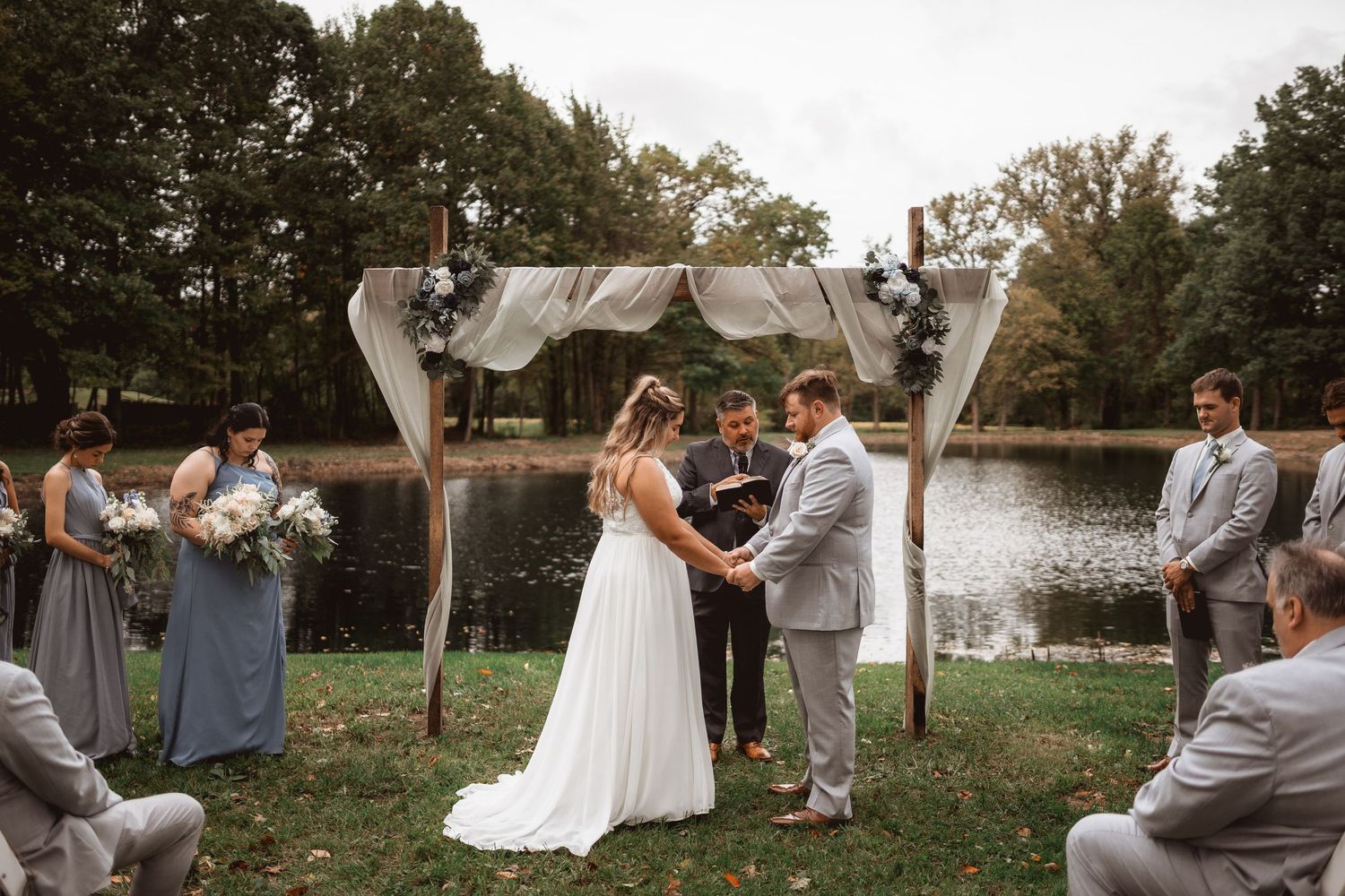 A picturesque outdoor wedding ceremony setup with white chairs and lakefront views.