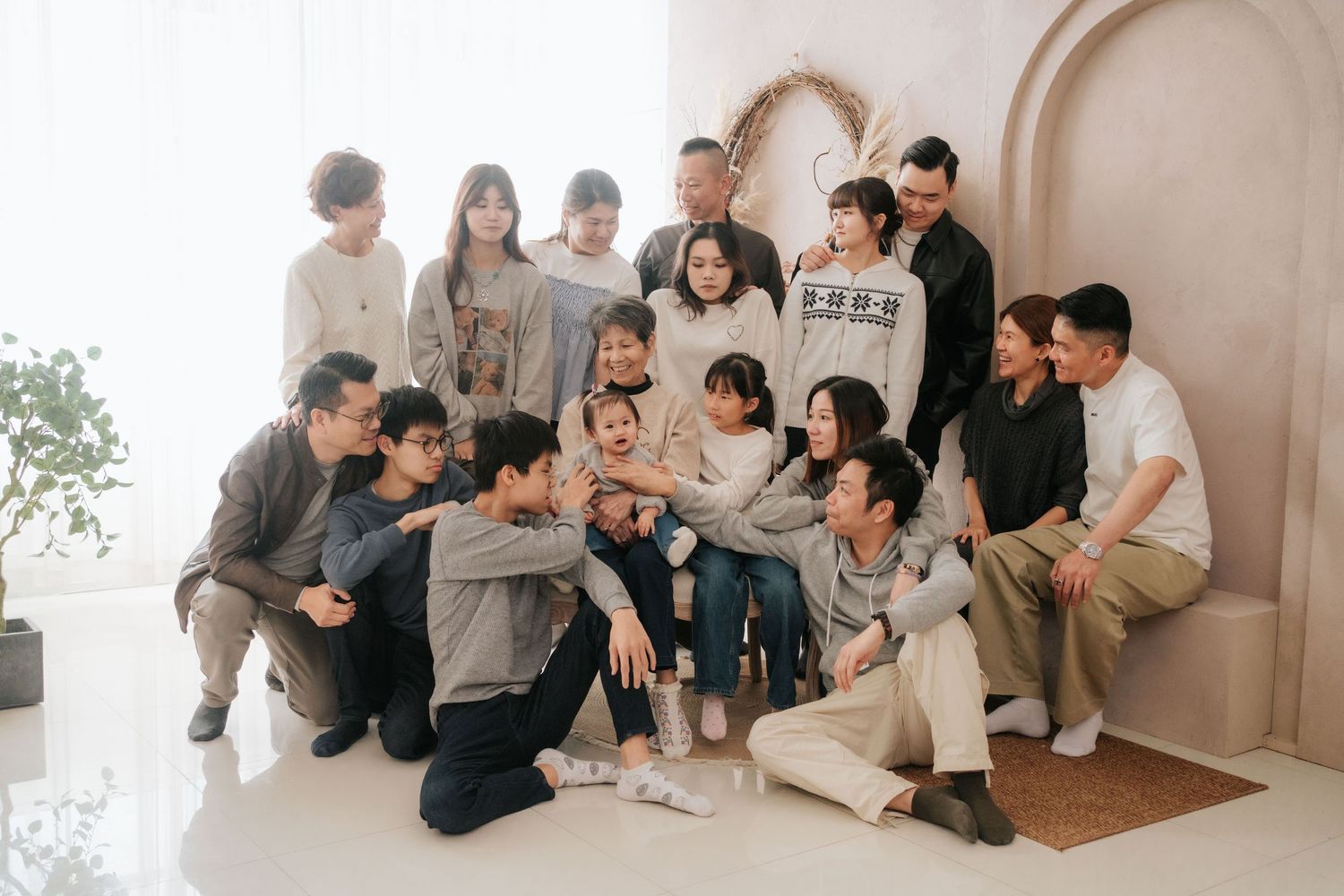 Group of friends sitting together on floor looking at photos and sharing memories in a bright indoor space.一群朋友坐在明亮的室內空間裡，一起坐在地板上看照片，分享回憶。